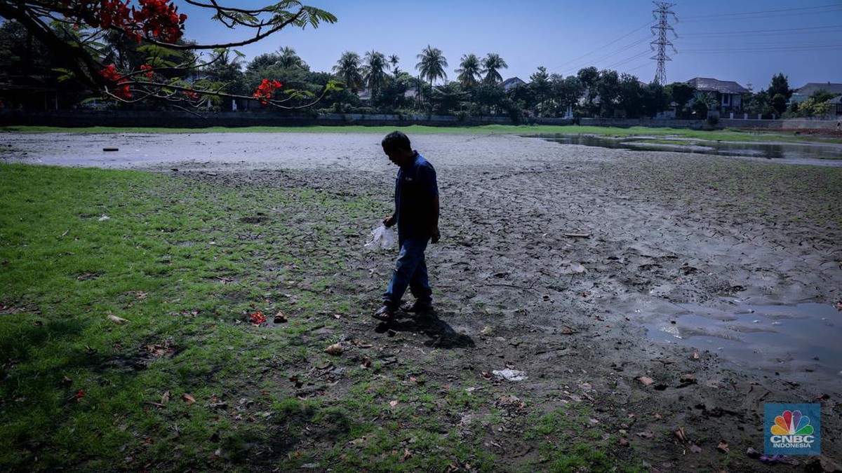 Foto: Seorang warga berjalan di tanah yang retak akibat kekeringan di Danau Cinere, Depok, Jawa Barat, Rabu (27/9/2023). (CNBC Indonesia/Faisal Rahman)
