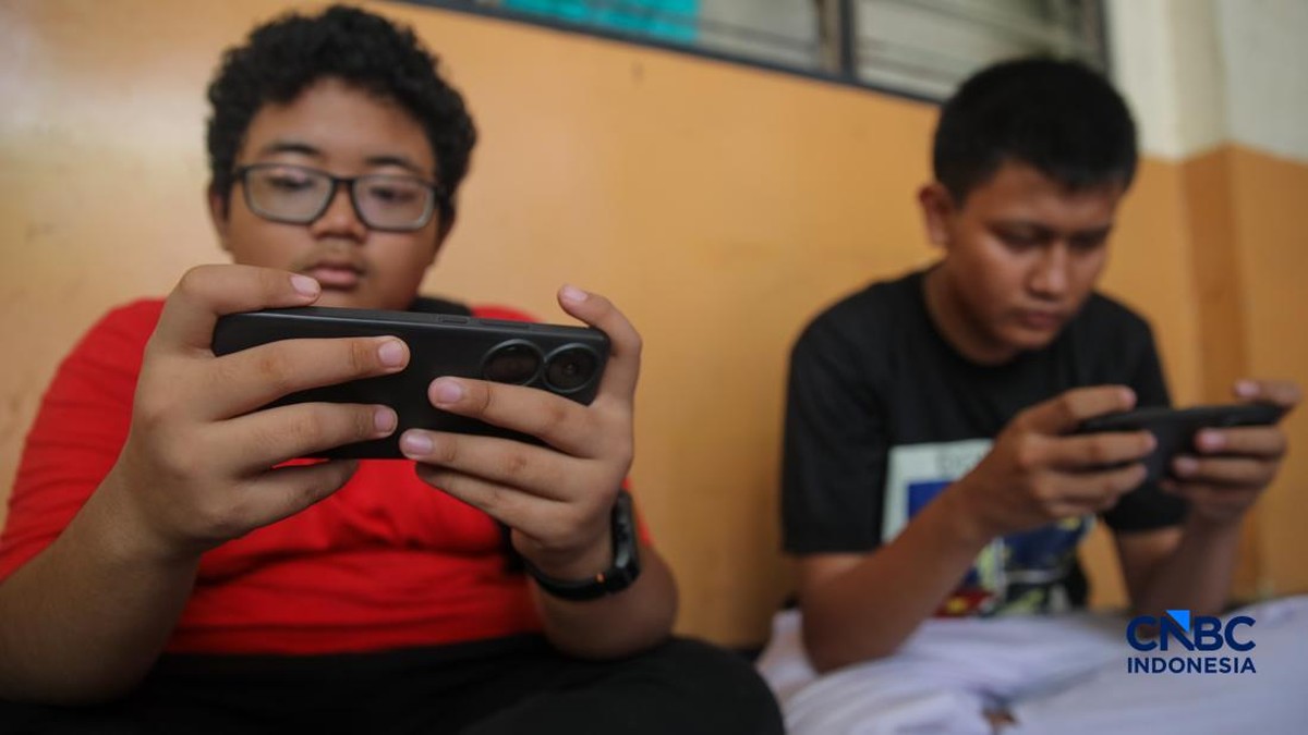 Foto: Sejumlah anak memainkan ponsel mereka sesuai pulang sekolah di Jakarta, Senin (30/3/2026). Pemerintah resmi melarang anak di bawah usia 16 tahun menggunakan media sosial mulai 28 Maret 2026 berdasarkan Peraturan Menteri Komunikasi dan Digital Nomor 9 Tahun 2026, yang merupakan turunan dari PP Tunas. (CNBC Indonesia/Faisal Rahman)