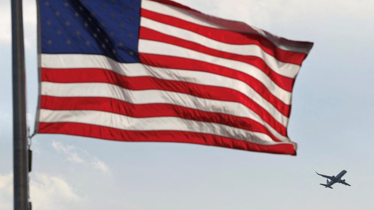 Foto: Sebuah pesawat terbang melewati sebuah bendera di Monumen Washington saat kekacauan perjalanan udara semakin dalam dengan lebih dari 2.700 penerbangan tertunda di seluruh negeri pada hari Senin karena penutupan pemerintah yang sedang berlangsung, di Washington, D.C., AS, 27 Oktober 2025. (REUTERS/Kevin Lamarque)