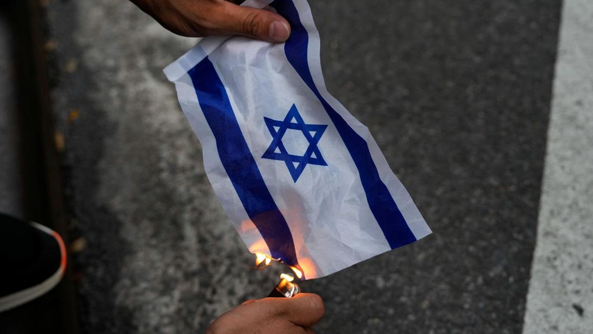 Foto: Seorang pendukung Pro-Palestina membakar bendera Israel saat mereka memprotes kampus City University of New York (CUNY) yang mengizinkan pembuatan film episode FBI: Most Wanted yang membuat fiksi Perkemahan Solidaritas Gaza di New York City, AS, 22 Juli 2024. (REUTERS/Adam Gray)