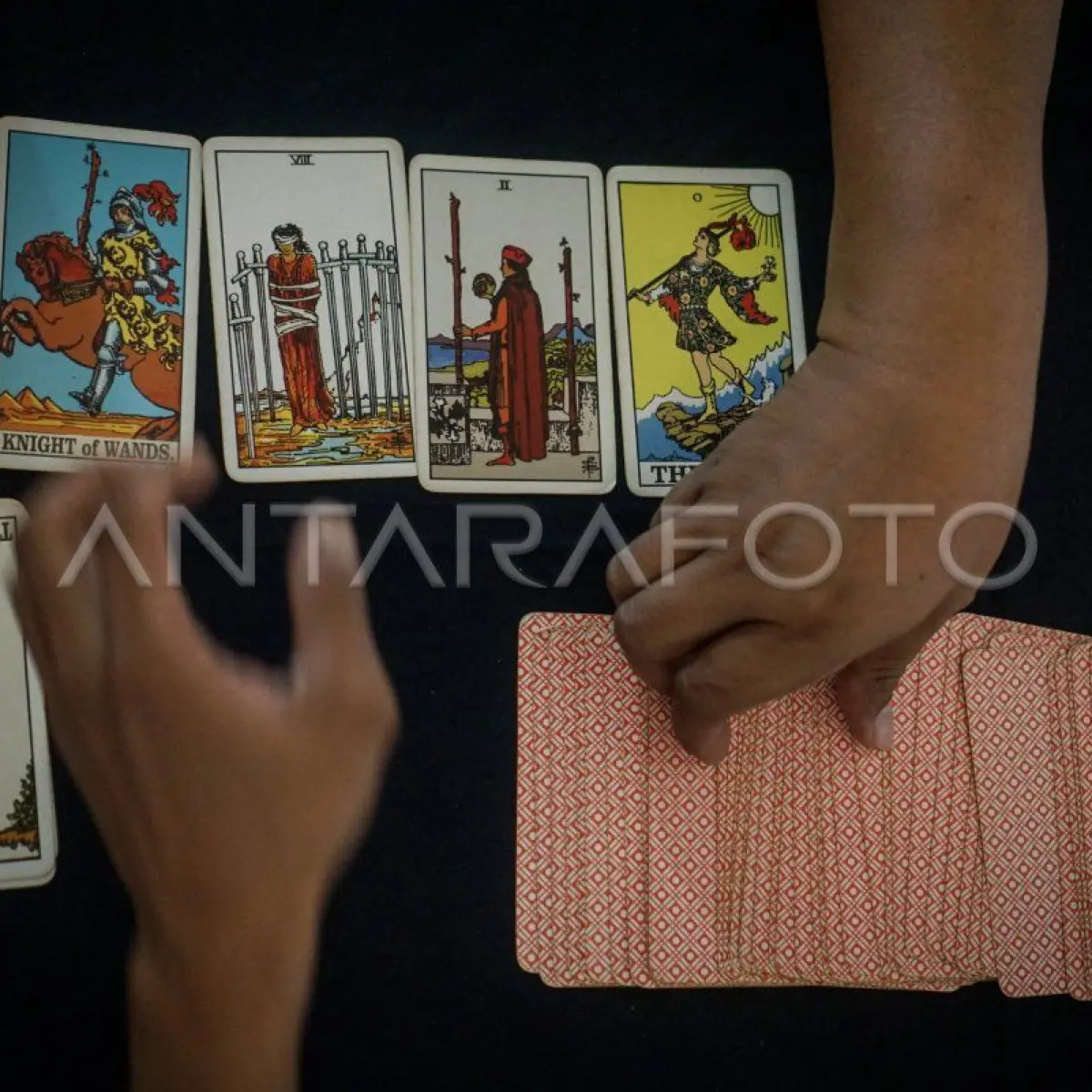 tangan memegang kartu tarot dengan latar cahaya redup (Foto: Antarafoto)