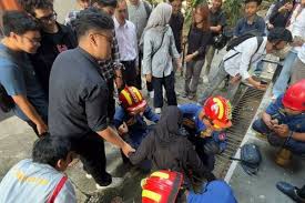 Petugas Damkar Solo mengevakuasi mahasiswi kakinya masuk sela-sela besi penutup selokan.(Dok Damkar Solo)