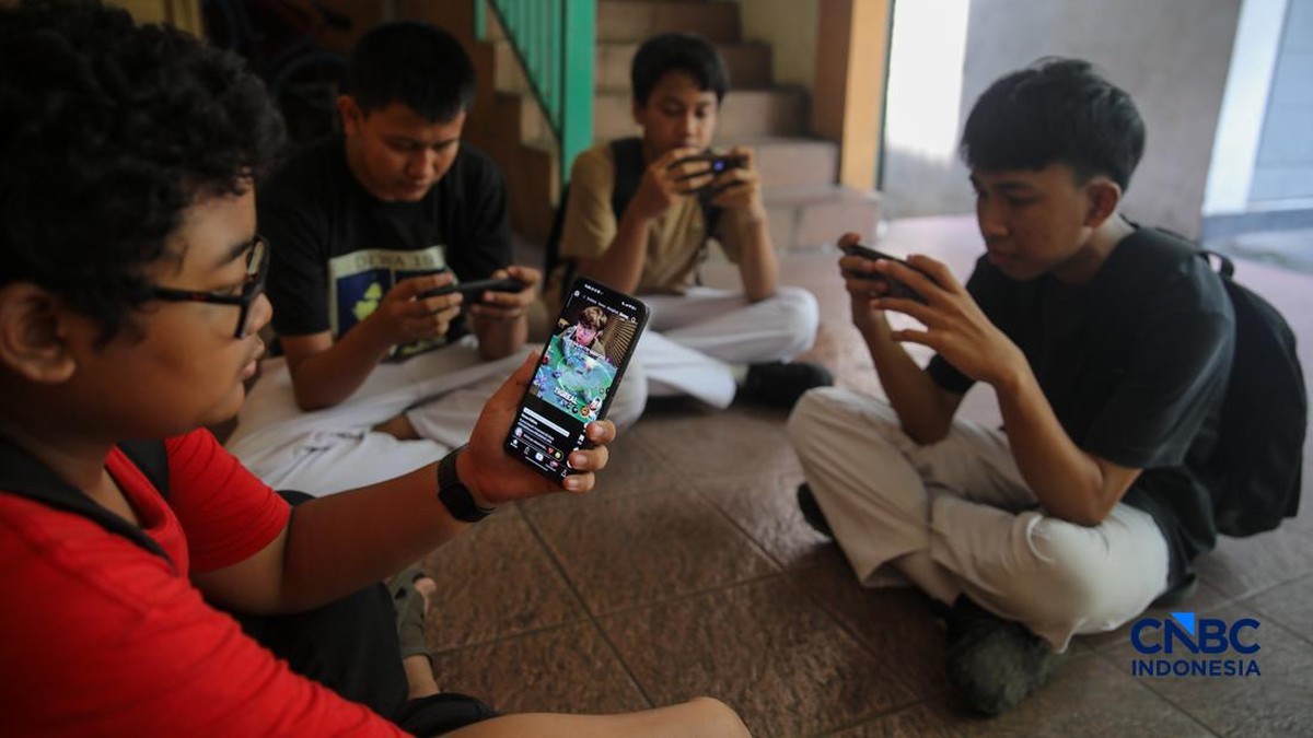 Foto: Sejumlah anak memainkan ponsel mereka sesuai pulang sekolah di Jakarta, Senin (30/3/2026). Pemerintah resmi melarang anak di bawah usia 16 tahun menggunakan media sosial mulai 28 Maret 2026 berdasarkan Peraturan Menteri Komunikasi dan Digital Nomor 9 Tahun 2026, yang merupakan turunan dari PP Tunas. (CNBC Indonesia/Faisal Rahman)