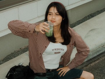 Callista Arum terlihat begitu santai duduk lesehan di pinggir jalanan Jepang sambil nyeruput minuman matcha dingin. Mengenakan kaus putih dipadu kemeja flanel kotak-kotak merah sebagai outer, penampilan bintang film Tumbal Proyek itu makin kece dengan celana pendek denim dan sepatu sneakers. (Foto: dok Instagram callistarum)