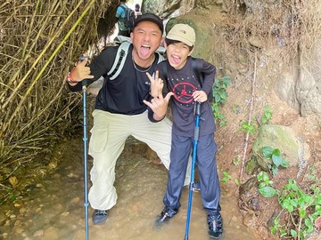 Omesh dan Langit berpose dengan latar belakang pemandangan sawah terasering yang hijau dan perbukitan asri. Cuaca cerah dengan awan putih berarak menambah keindahan momen ini. Ayah dan anak ini terlihat kompak membawa tongkat pendaki. (Foto: dok Instagram omeshomesh)