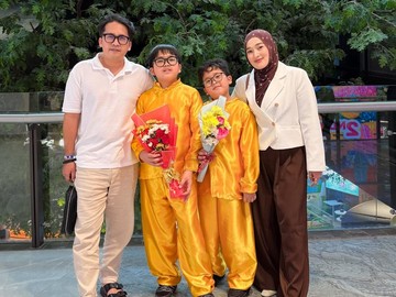 Ririe Fairus tampil anggun mengenakan blazer putih dipadu dengan jilbab motif cokelat, sementara Ayus tampil santai dengan kaos polo putih dan celana krem. Bersama kedua putra mereka, Bian dan Ben, yang kompak mengenakan setelan berwarna kuning emas cerah sambil membawa buket bunga, senyum semringah terpancar jelas dari wajah Ririe. (Foto: dok Instagram ririe_fairus)