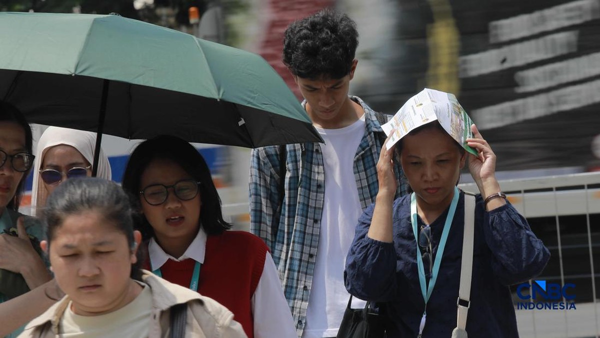 Foto: Warga berjalan dengan menutup kepala untuk berlindung dari terik matahari di Sudirman, Jakarta, Rabu (29/4/2026). (CNBC Indonesia/Muhammad Sabki)