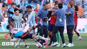 Keterangan gambar, Thiago Almada dan Leandro Paredes menjatuhkan Gavi ke lapangan, sementara Roberto Ayala tampak memegang leher Eric Garcia di tengah kericuhan yang terjadi usai pertandingan final Piala Dunia 2026, Senin (20/07).