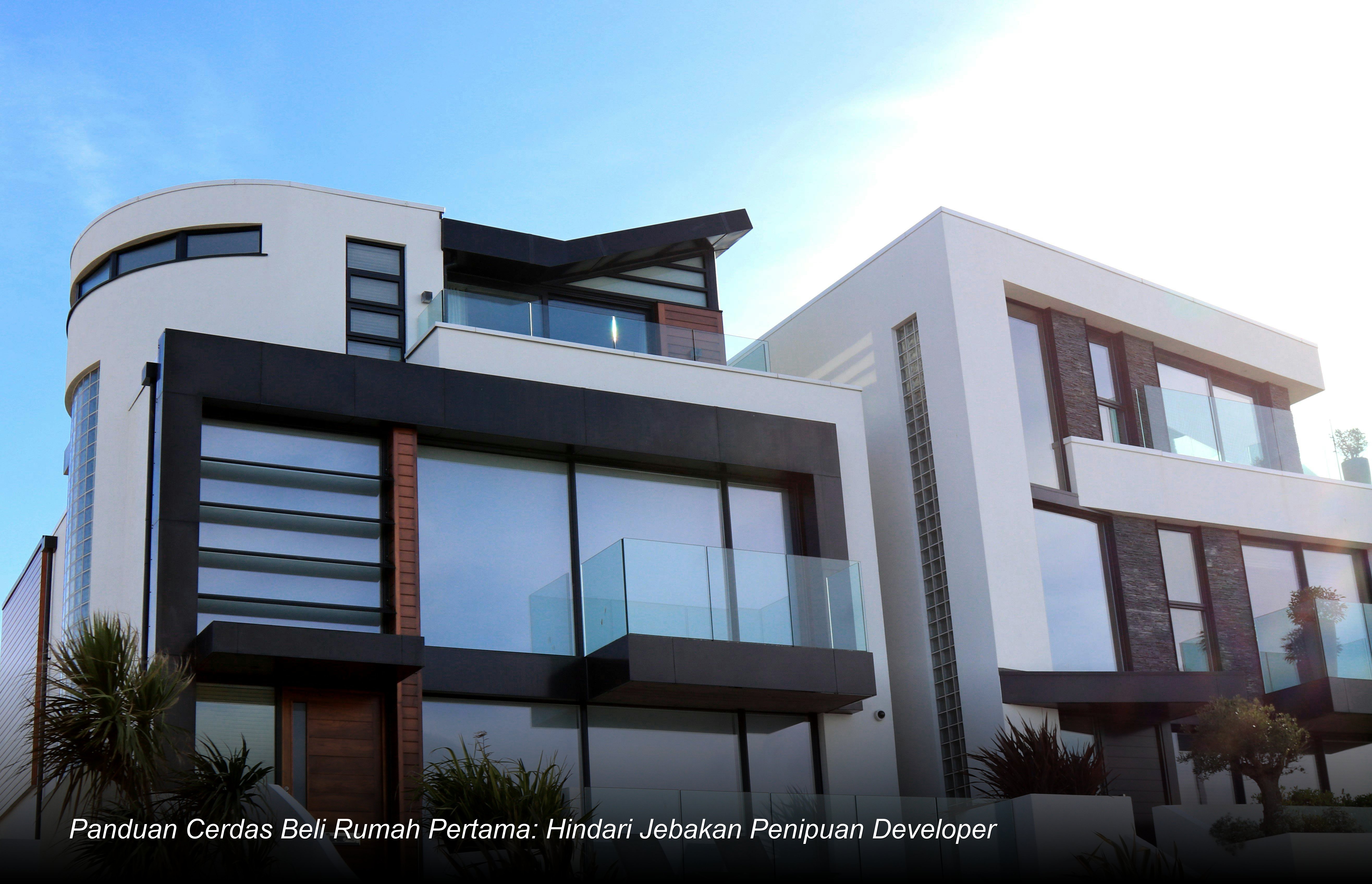 Seorang pasangan muda sedang menandatangani dokumen akad kredit di hadapan notaris dengan latar belakang maket rumah minimalis modern.